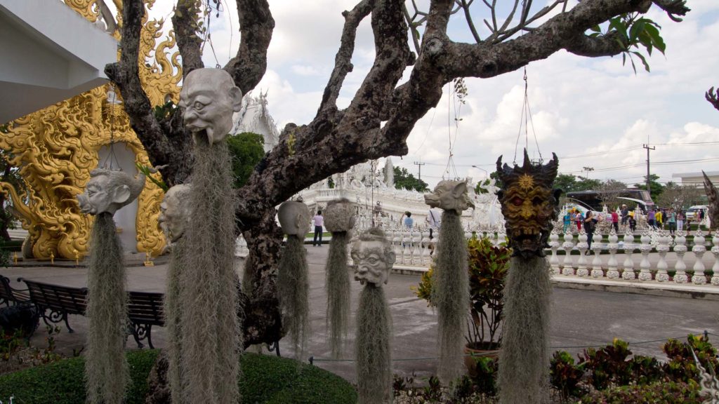 Abschreckende Gesichter an den Bäumen im weißen Tempel von Chiang Rai