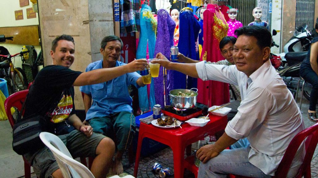 Einheimische mit Marcel beim Essen und Trinken auf der Straße, Ho Chi Minh City