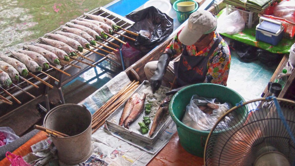 Fisch wird auf einem Boot des Taling Chan Floating Market in Bangkok zubereitet