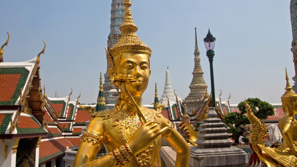 Statue mit Chedis im Hintergrund im Wat Phra Kaeo in Bangkok