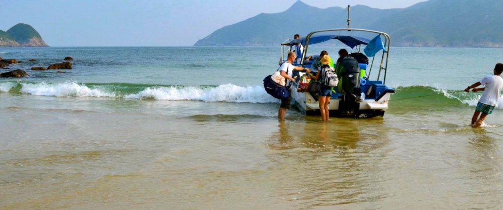 Boot mit Touristen legt am Sai Wan Beach in Hong Kong an