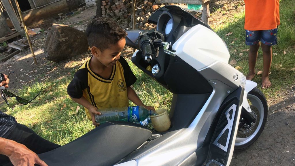 Child refueling the scooter in Flores, Indonesia