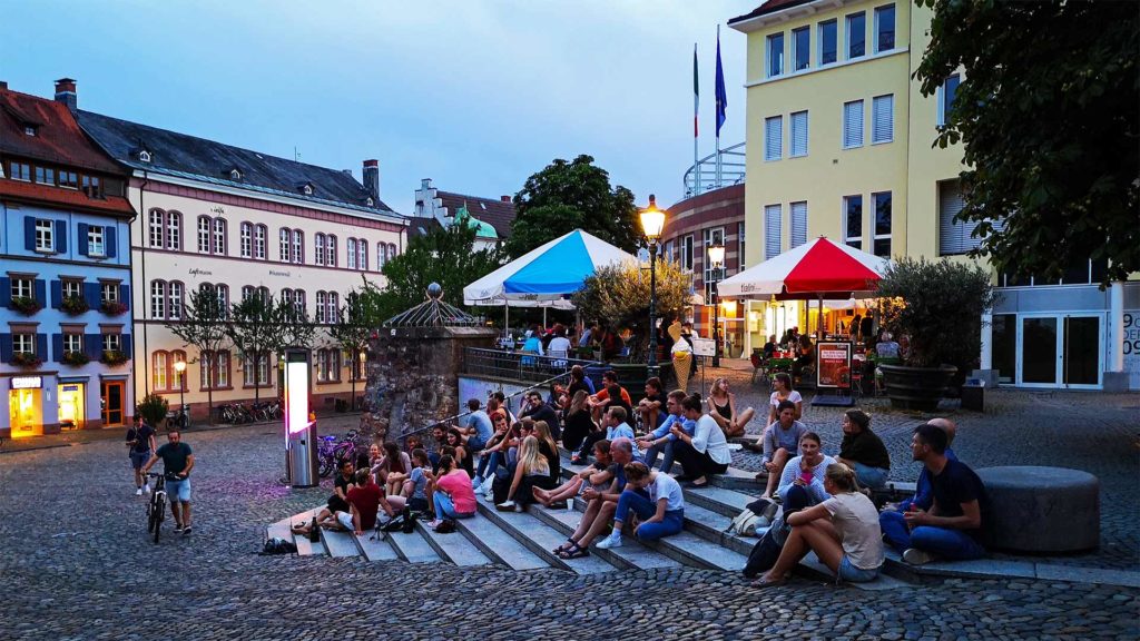 Menschen am Abend auf dem Augustinerplatz in Freiburg