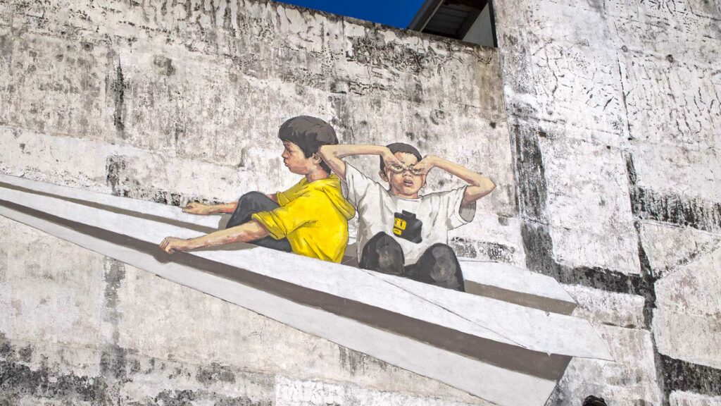 Zwei Kinder auf Papierflieger Street Art in Ipoh, Malaysia