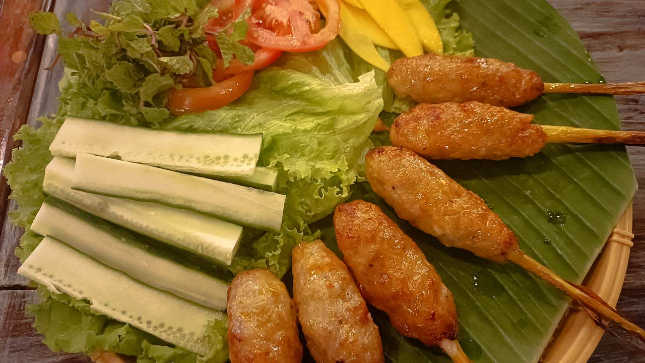 Vietnamesische Fleischspieße mit frischem Gemüse, auf einem Bananenblatt serviert